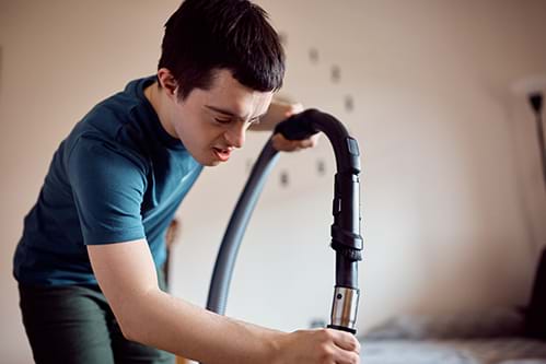 Young person with a disability vacuuming a house as part of a Supported Employment program 